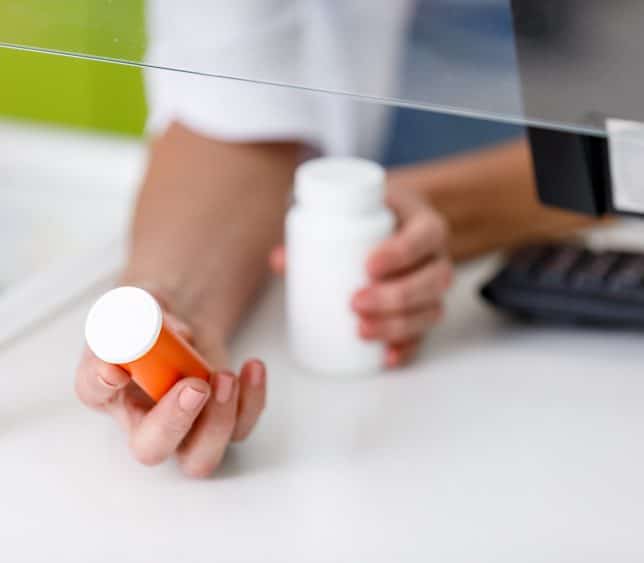 Pharmacist holding out two bottle from counter - TeleLeaf